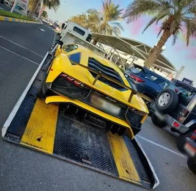 Luxury car towing service in Abu Dhabi loading sports car onto recovery truck
