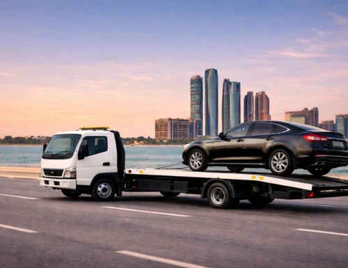Car towing service in Abu Dhabi transporting a black car on flatbed truck